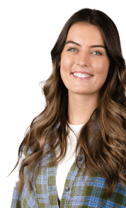 A smiling person with long, wavy brown hair sports a green and blue plaid shirt over a white top, embodying confidence akin to an enterprise SEO agency.