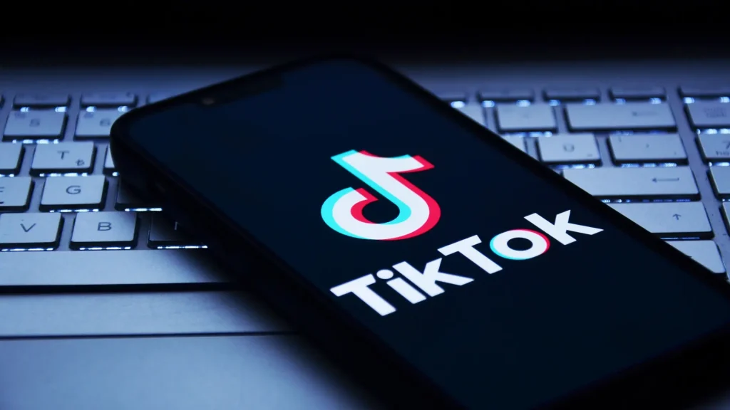 TikTok logo displayed on a mobile device above a keyboard, symbolising TikTok Ads Manager updates and AI-driven campaign guidance for social advertising.